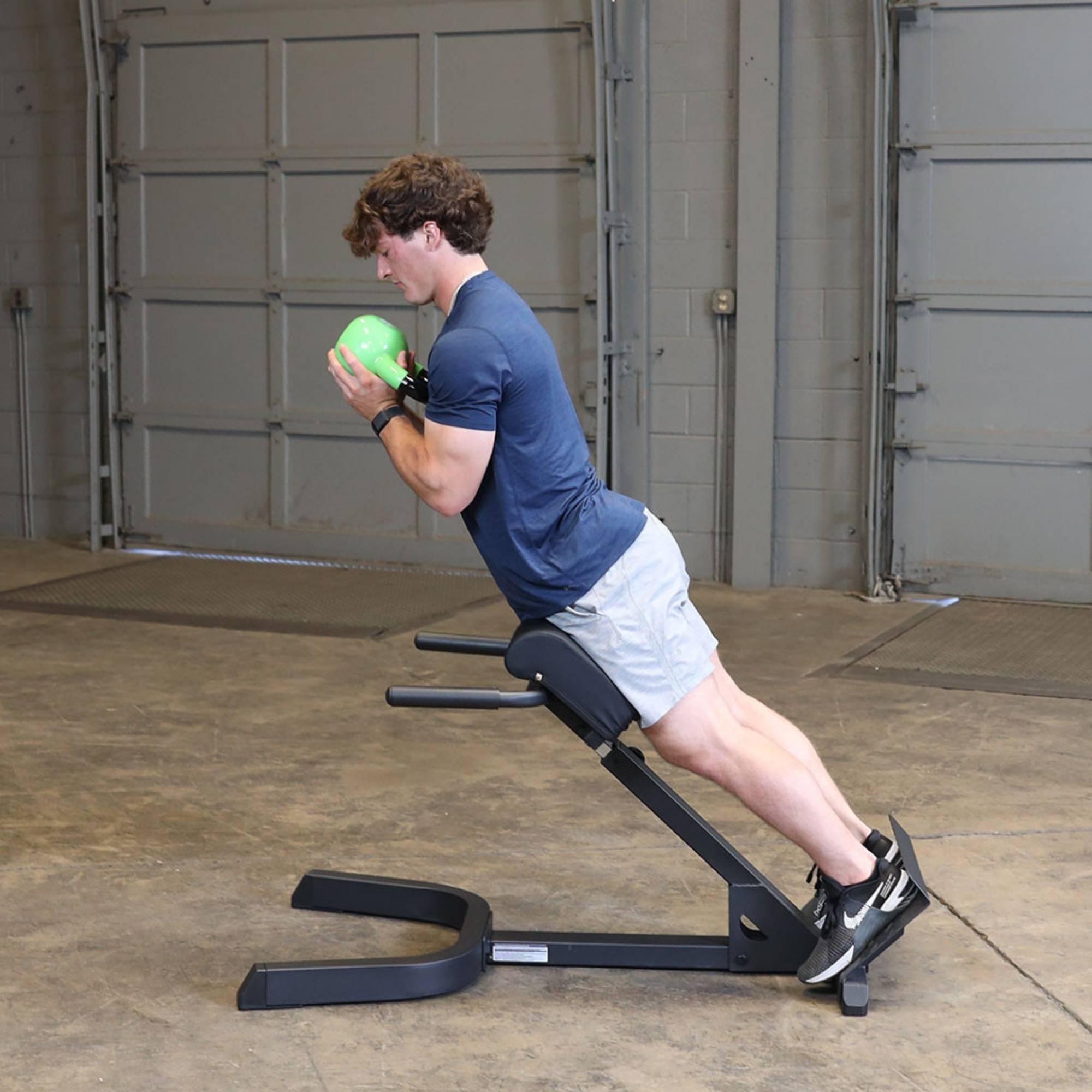 Body-Solid 45 Back Hyperextension GHYP345B Man holding medicine ball at chest height during GHYP345B back extension