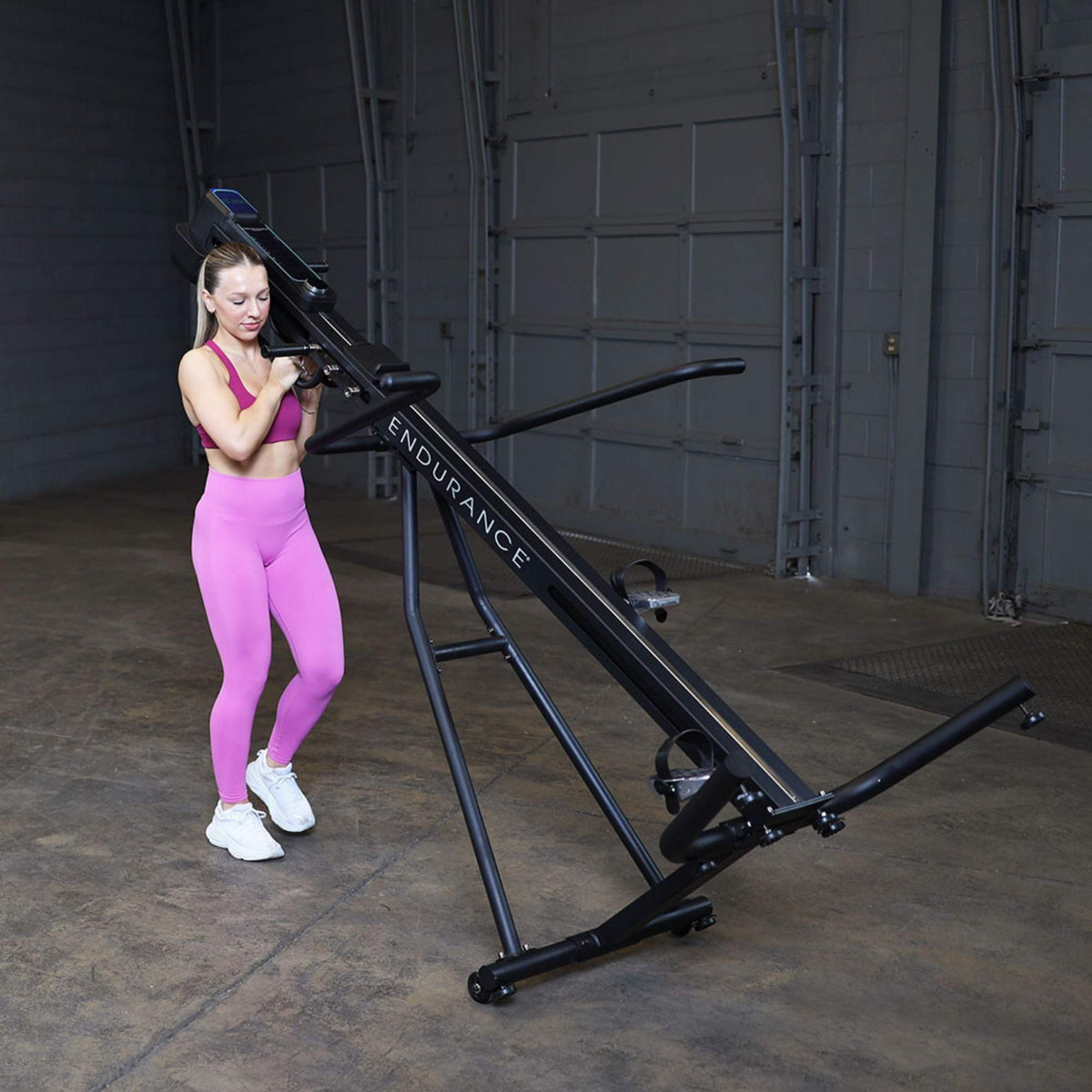 Body-Solid Climber Endurance CL300 Woman tilting using transport wheels for storage or repositioning