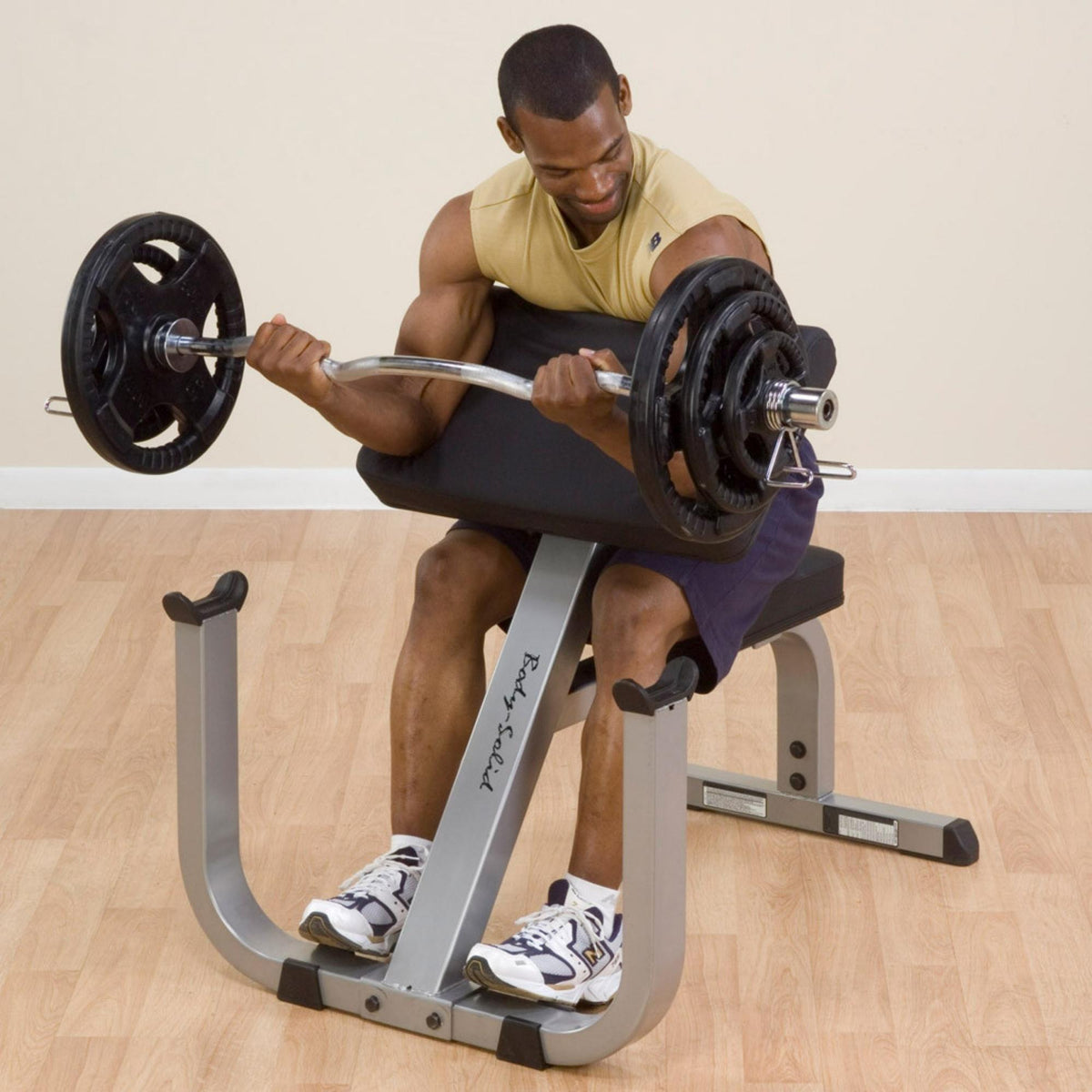 Body-Solid Preacher Curl Bench GPCB329B Man performing barbell curls on a Body-Solid preacher curl bench in a home gym