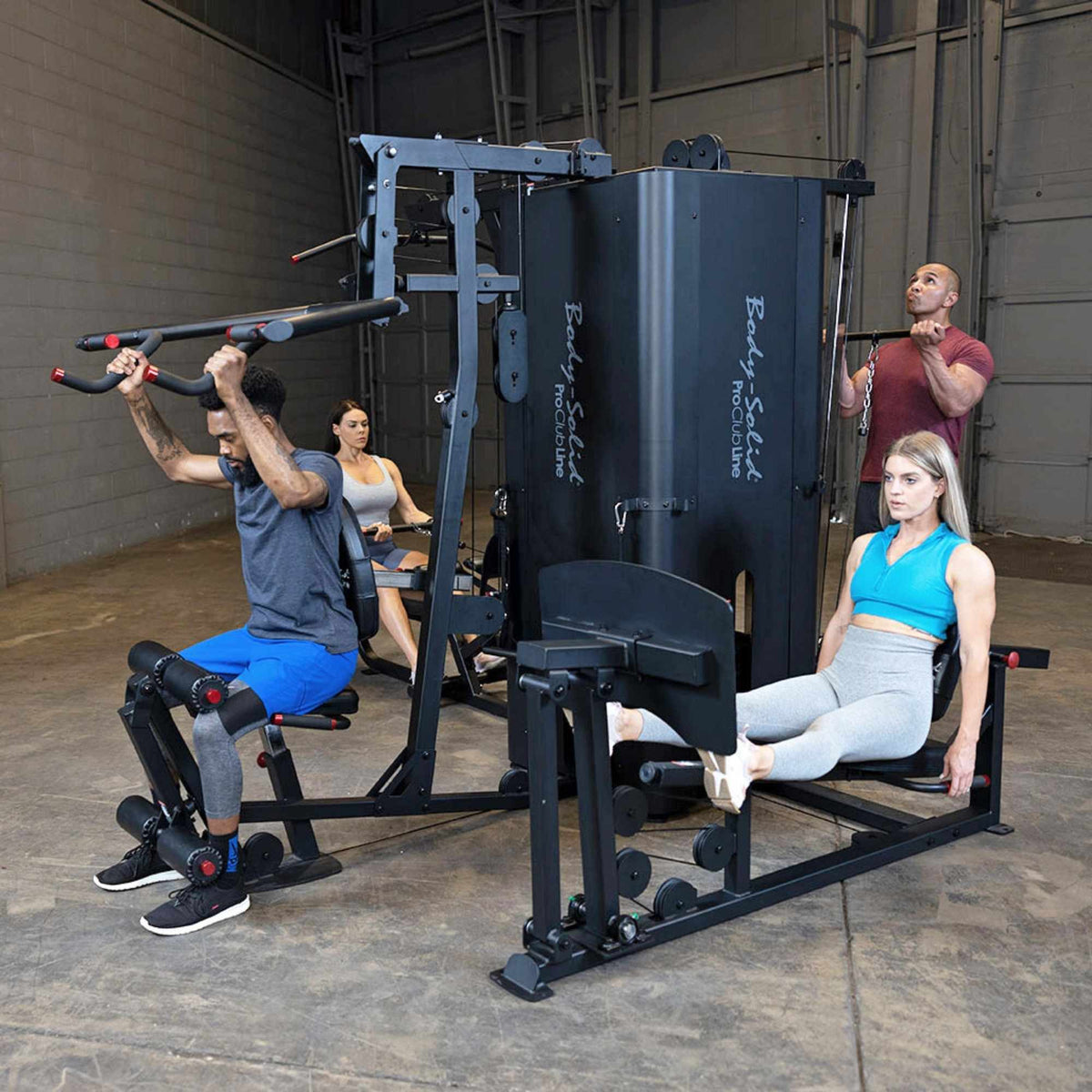 Body-Solid Pro ClubLine Four-Stack Gym S1000 multi-gym with users doing lat pull, leg press, and chest fly exercises