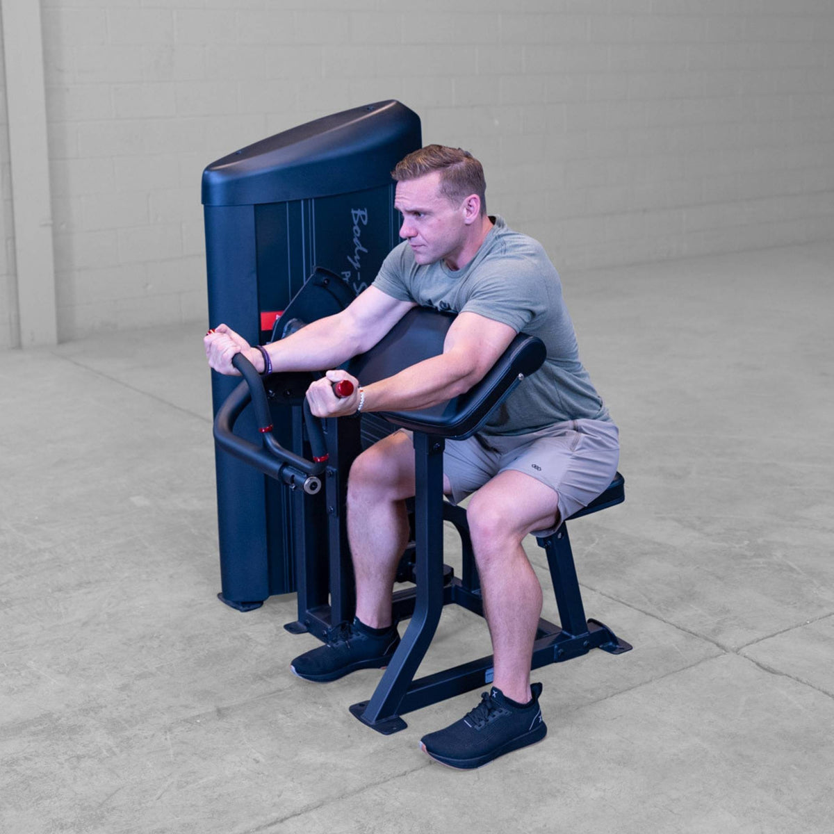 Body-Solid Pro ClubLine Series 2 Arm Curl S2ACX Man seated and engaging in isolated bicep curl exercise on Body-Solid ProClubLine arm curl machine.