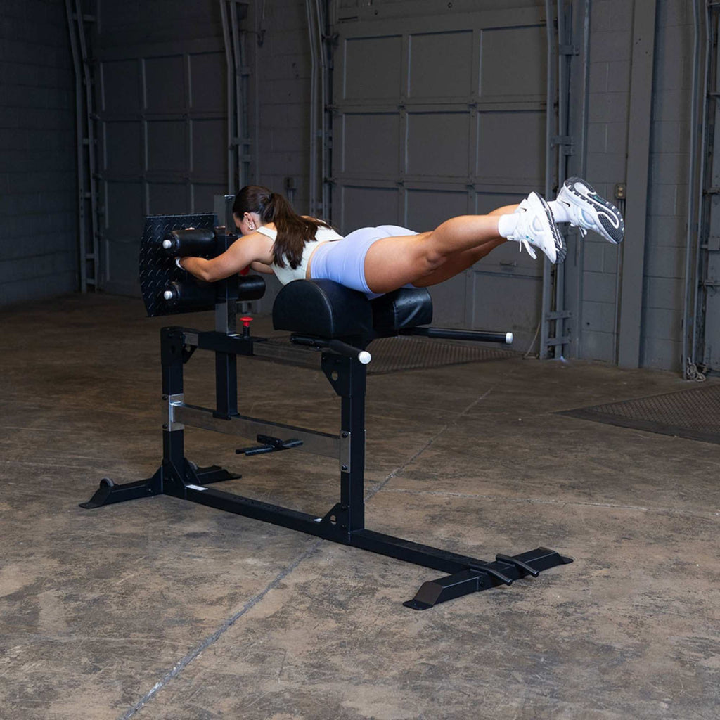 GHD & Hyperextension Machines - woman performing lower back extension and able to hit a superman pose with her strong core muscles