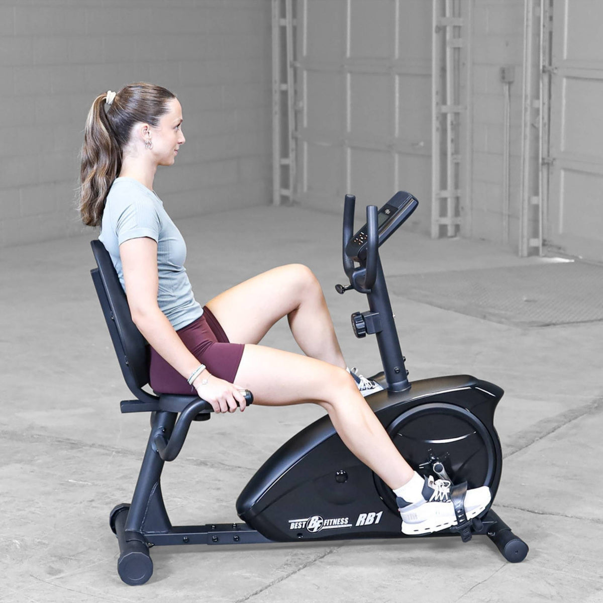 Best Fitness Recumbent Bike BFRB1B Female athlete performing steady-state cardio on Best Fitness RB1 recumbent bike in an open studio space.