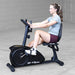 Best Fitness Recumbent Bike BFRB1B Side view of woman exercising on Best Fitness RB1 recumbent bike, demonstrating ergonomic back support.