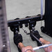 Close-up of a person using a cable pulley on a Body-Solid-GSFR-100All-in-OneFunctional-Trainer-Smith-Machine  in a gym, with their feet resting on footrests and hands pulling a bar with a chain attachment.