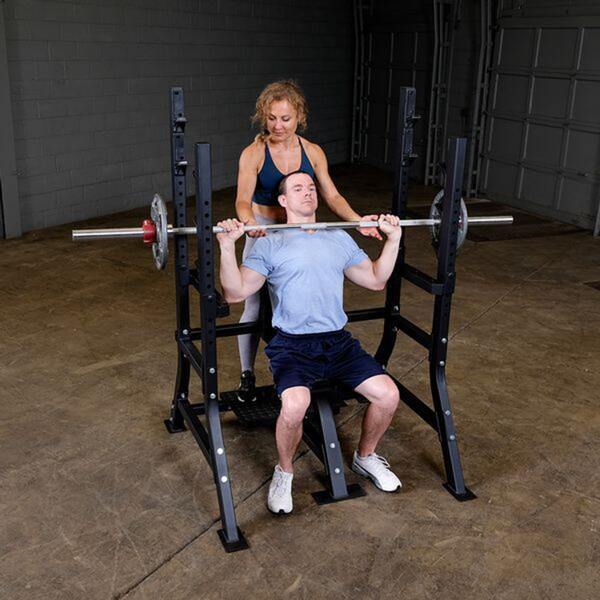 Body-Solid Pro Clubline Olympic Shoulder Press Bench SOSB250 with spotter and user exercising a milltary press
