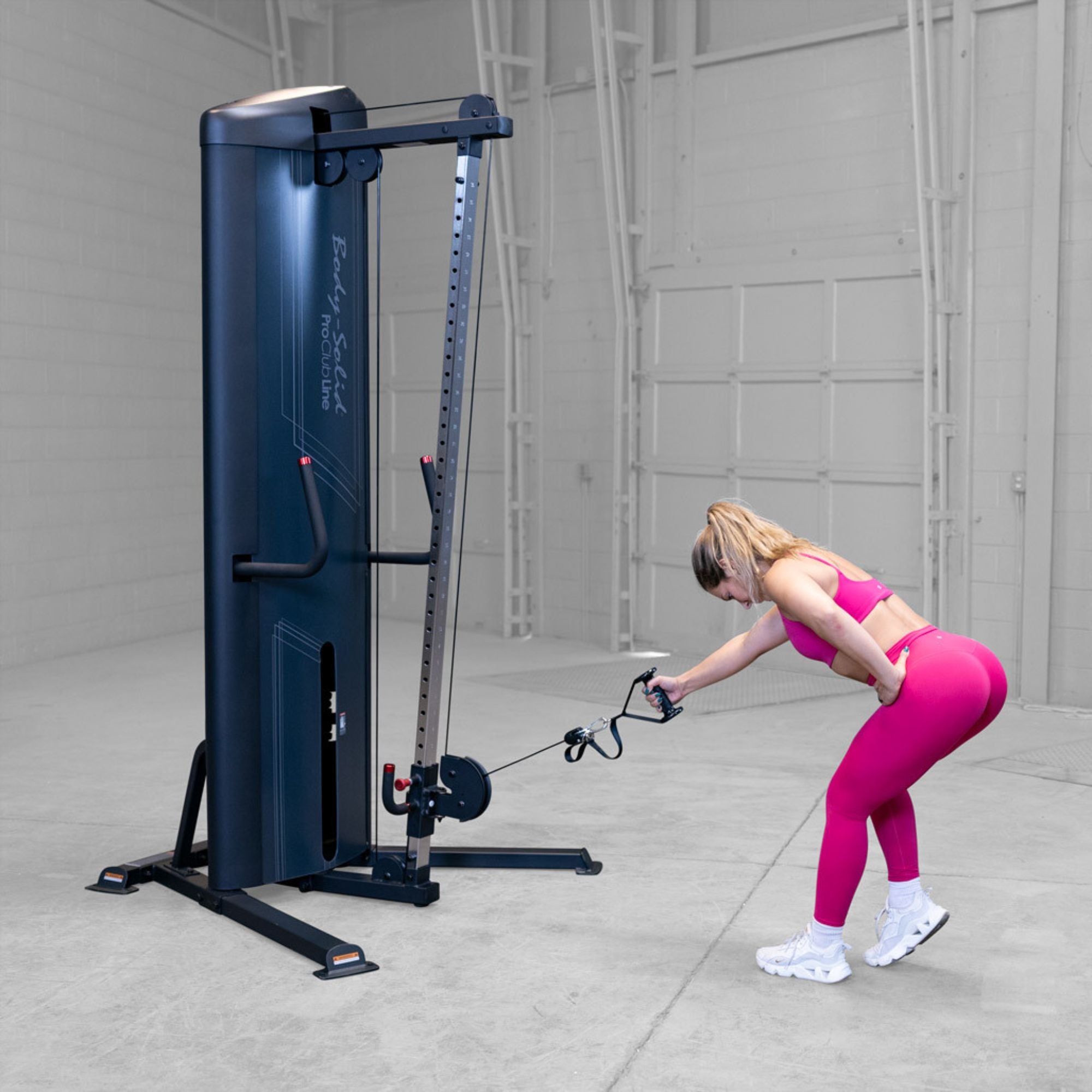 Body-Solid-S2CC-Series-2-Cable-Column-Single-Arm-Bent-Over-Cable-Rear-Delt-Fly. Woman exercising on a cable machine in a gym setting