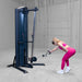Body-Solid-S2CC-Series-2-Cable-Column-Single-Arm-Bent-Over-Cable-Rear-Delt-Fly. Woman exercising on a cable machine in a gym setting
