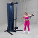 Body-Solid-S2CC-Series-2-Cable-Column-Single-Arm-Cable-Lateral-Raise. Woman exercising on a cable machine in a gym setting
