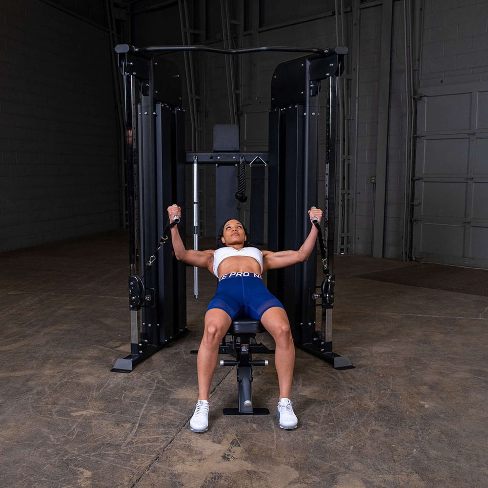 Woman doing a chest fly on a bench, with the Body-Solid Functional Trainer GFT100 
