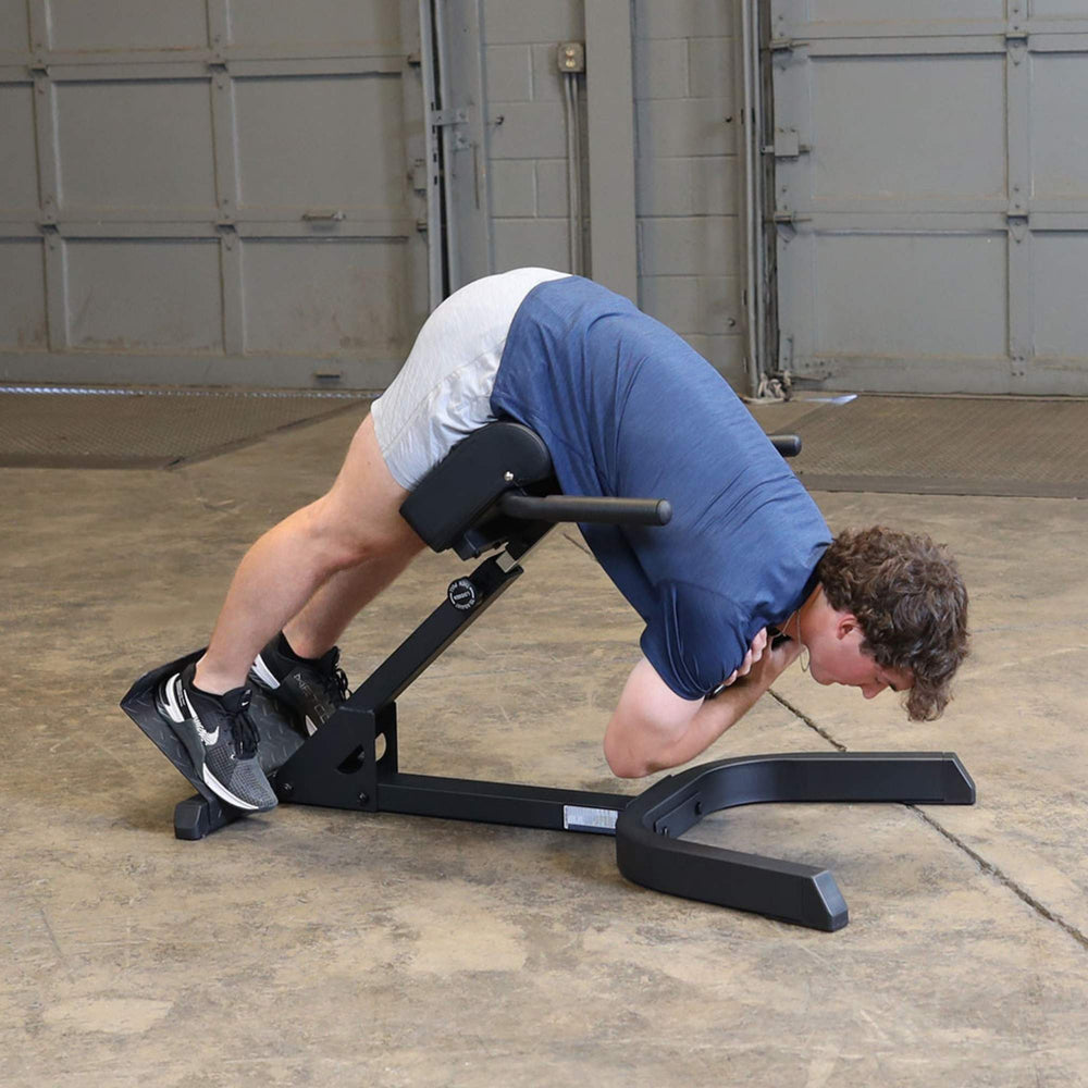 Body-Solid 45 Back Hyperextension GHYP345B Man performing full extension exercise on hyperextension bench with hands crossed over chest