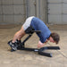 Body-Solid 45 Back Hyperextension GHYP345B Man performing full extension exercise on hyperextension bench with hands crossed over chest