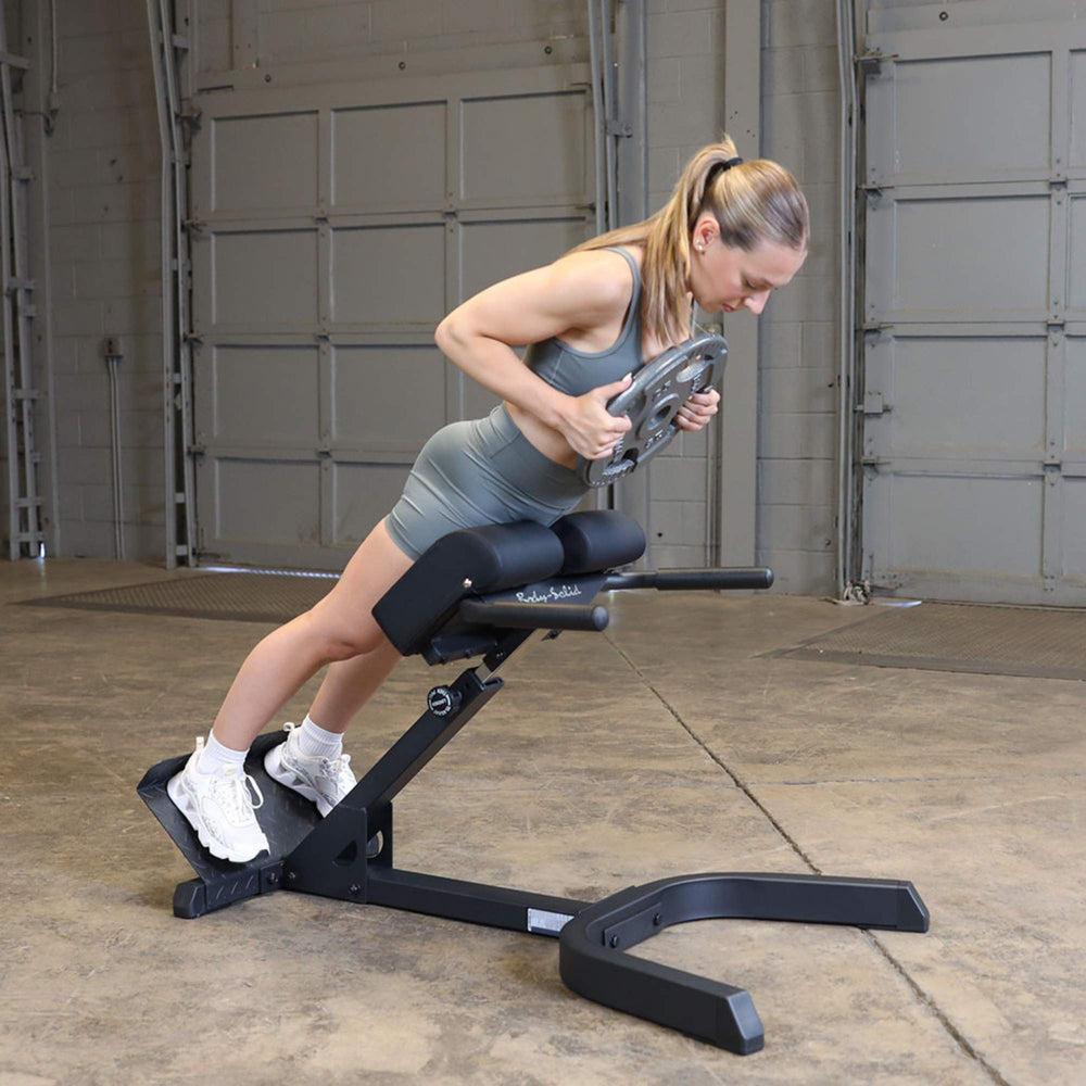 Body-Solid 45 Back Hyperextension GHYP345B Woman doing weighted hyperextension
