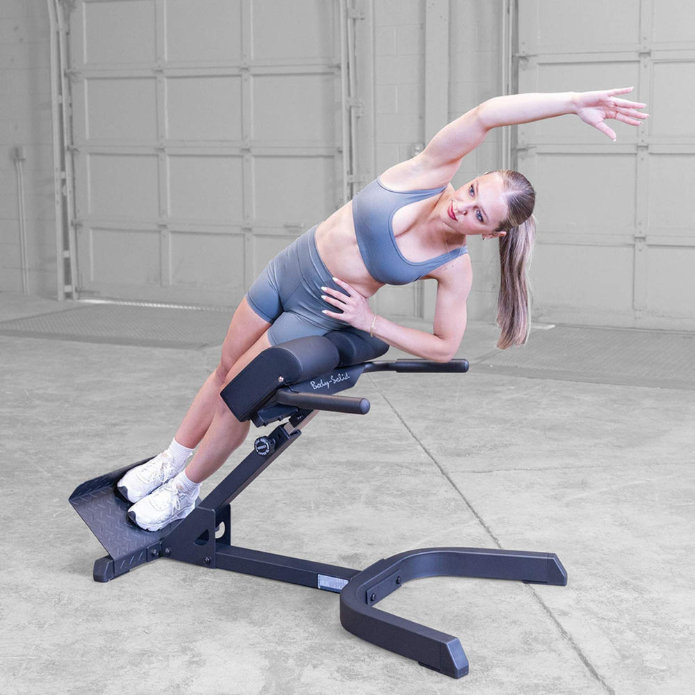Body-Solid 45 Back Hyperextension GHYP345B Woman stretching obliques over hyperextension bench