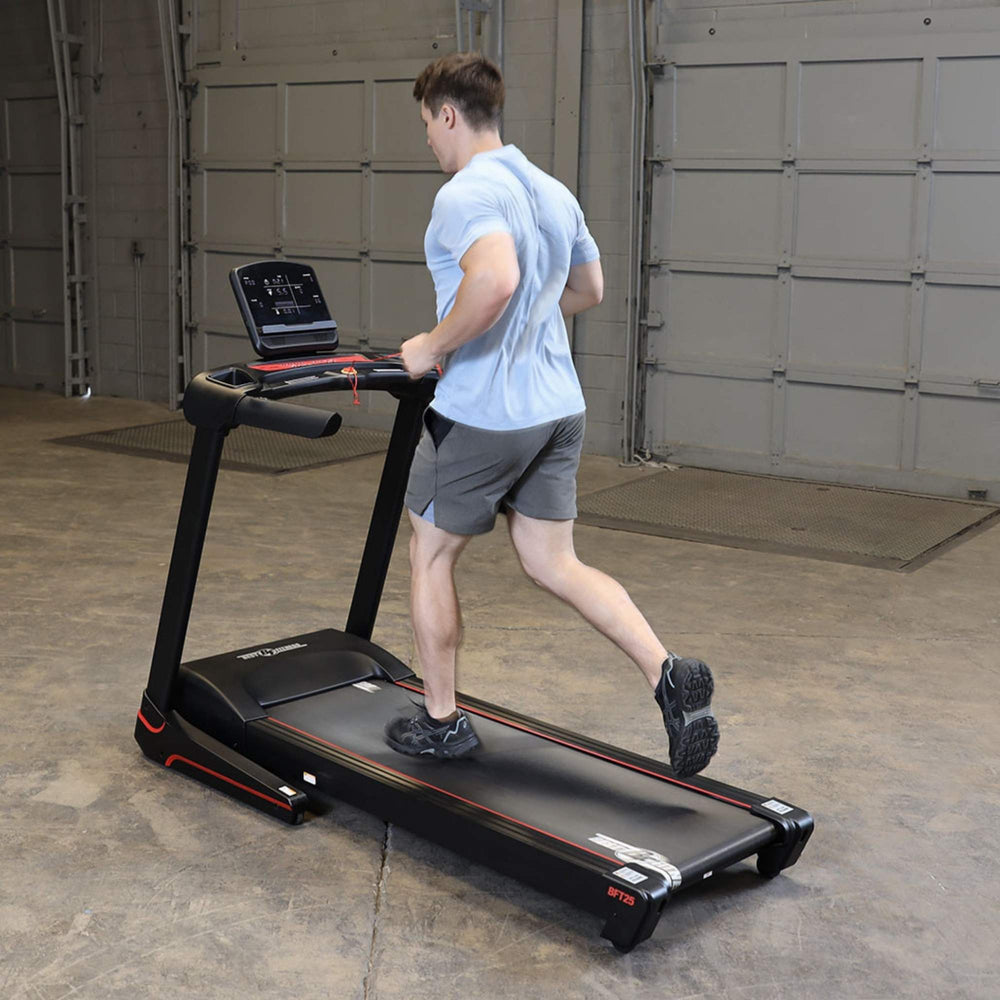 Body-Solid Best Fitness Folding Treadmill With LED Console BFT25 Man performing cardio exercise on Best Fitness treadmill with incline