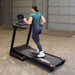 Body-Solid Best Fitness Folding Treadmill With LED Console BFT25 Rear view of woman jogging on Best Fitness treadmill in indoor gym
