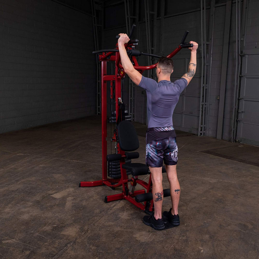Body-Solid Best Fitness Multi-Station Gym BFMG30 Rear view of man doing overhead shoulder press on red home gym