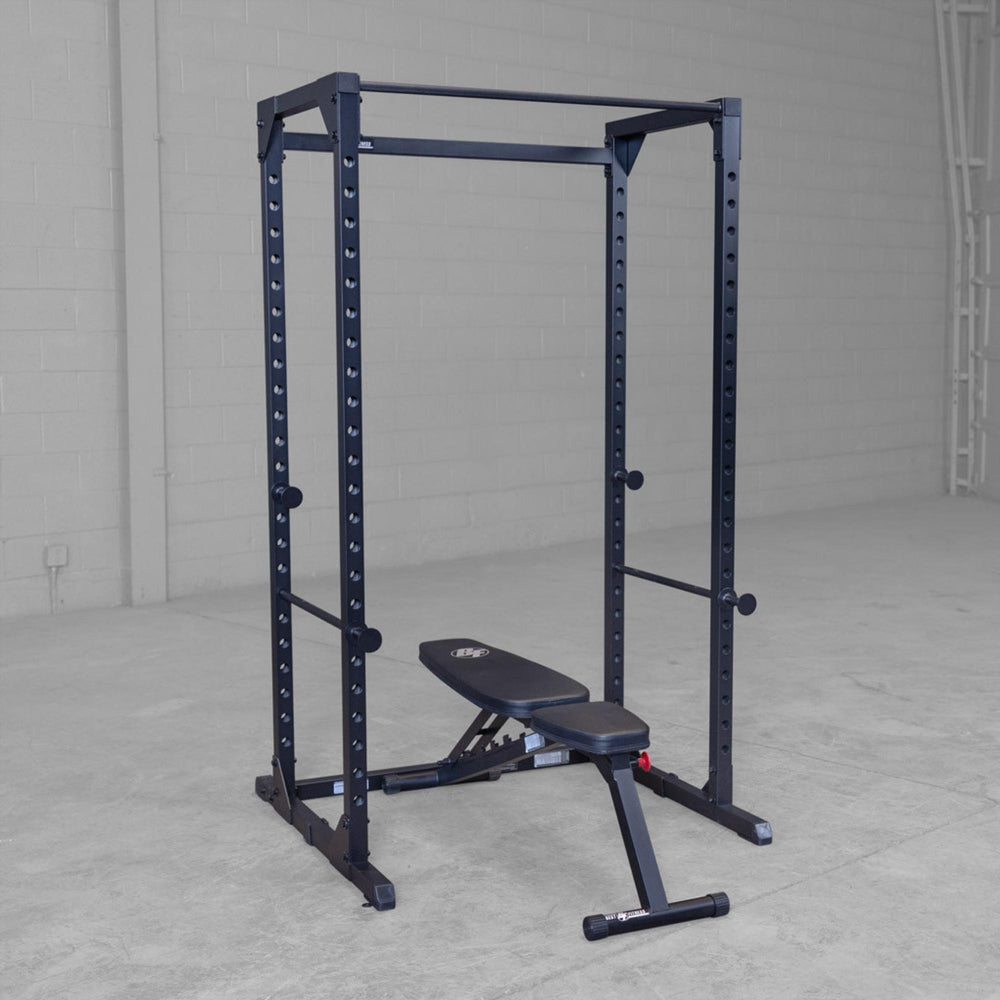 Body-Solid Best Fitness Power Rack BFPR100B Empty black power rack with adjustable bench positioned inside a spacious gym setup.

