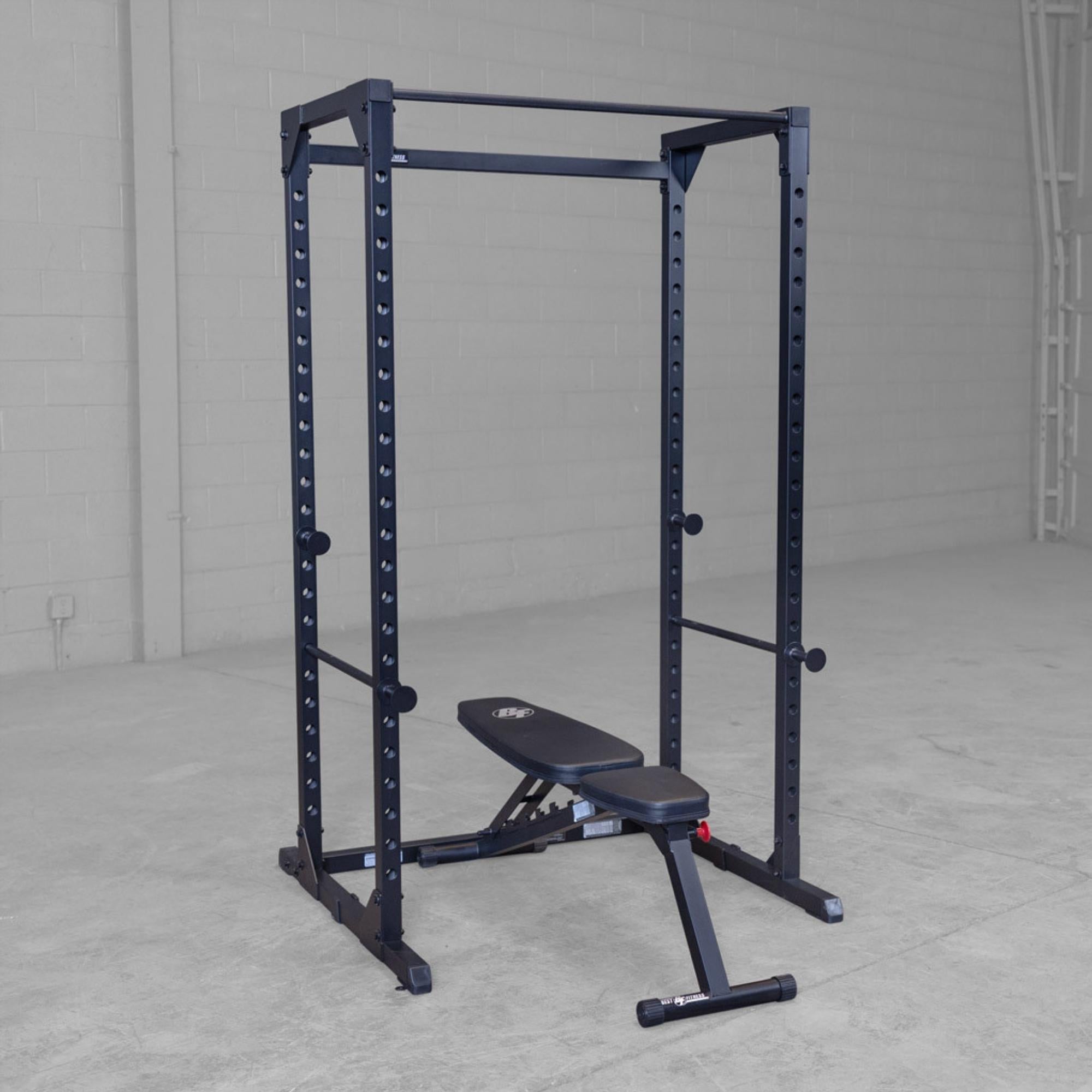 Body-Solid Best Fitness Power Rack BFPR100B Empty black power rack with adjustable bench positioned inside a spacious gym setup.

