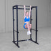 Body-Solid Best Fitness Power Rack BFPR100B Woman hanging from power rack performing a hanging leg raise exercise.
