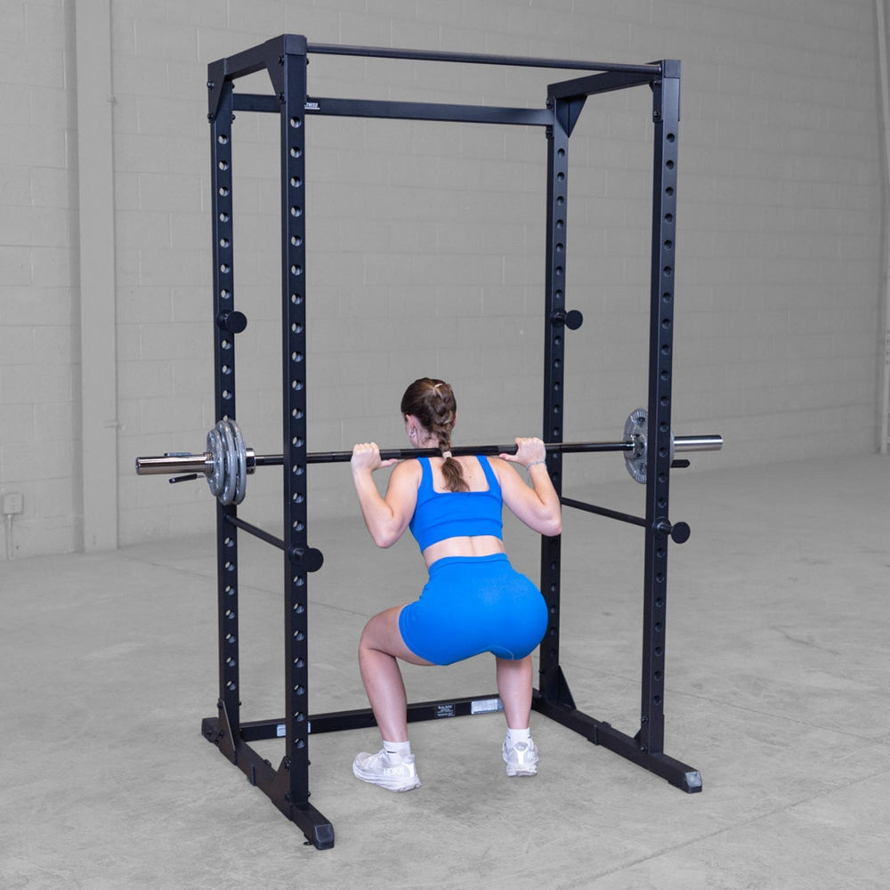 Body-Solid Best Fitness Power Rack BFPR100B Woman performing back squat with barbell inside a sturdy power rack.
