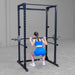Body-Solid Best Fitness Power Rack BFPR100B Woman performing back squat with barbell inside a sturdy power rack.

