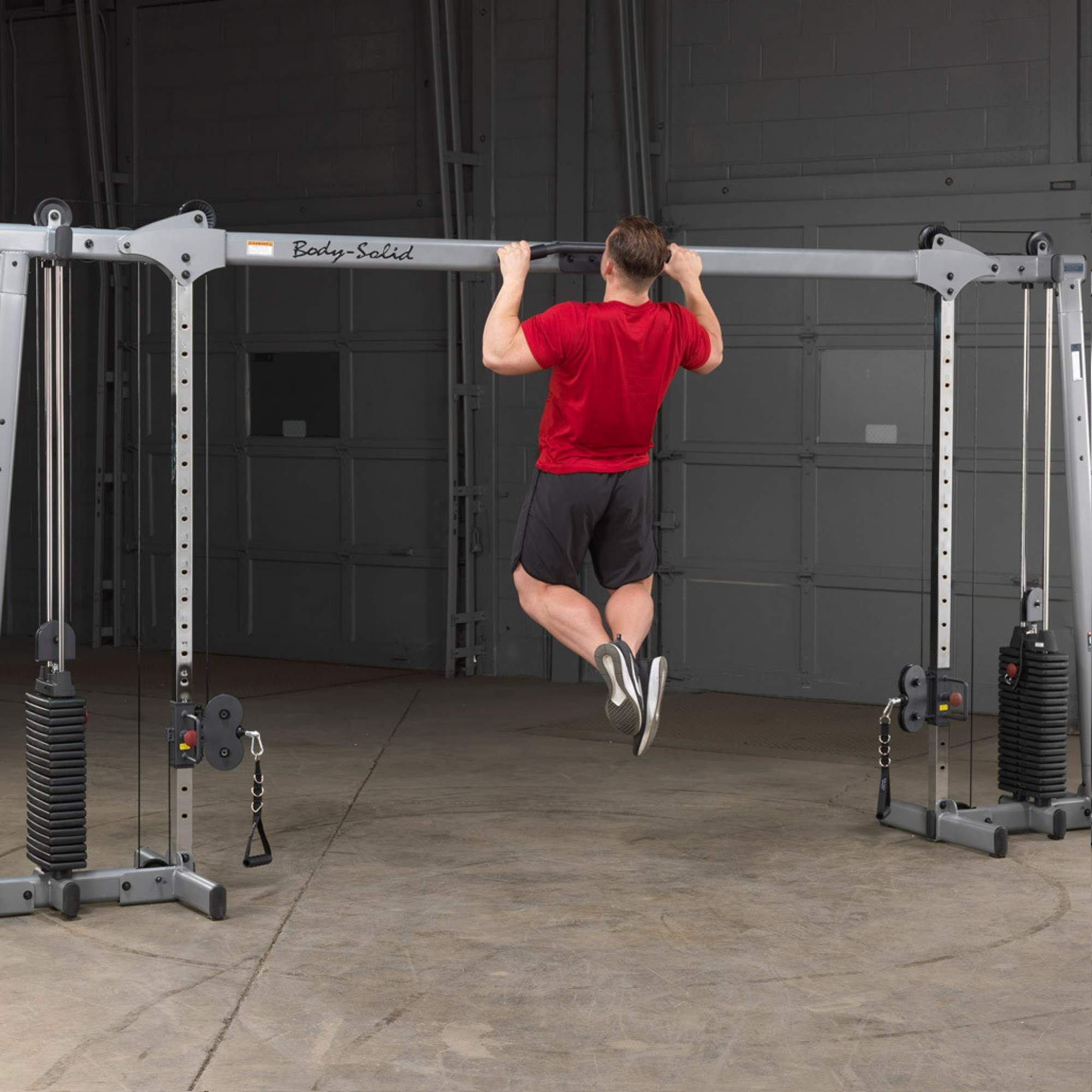 Body-Solid Cable Crossover GDCC250B Man doing pull-up on functional trainer with weight stacks
