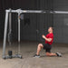 Body-Solid Cable Crossover GDCC250B Man kneeling while performing lat pulldown with  cable crossover machine to engage upper back and lats