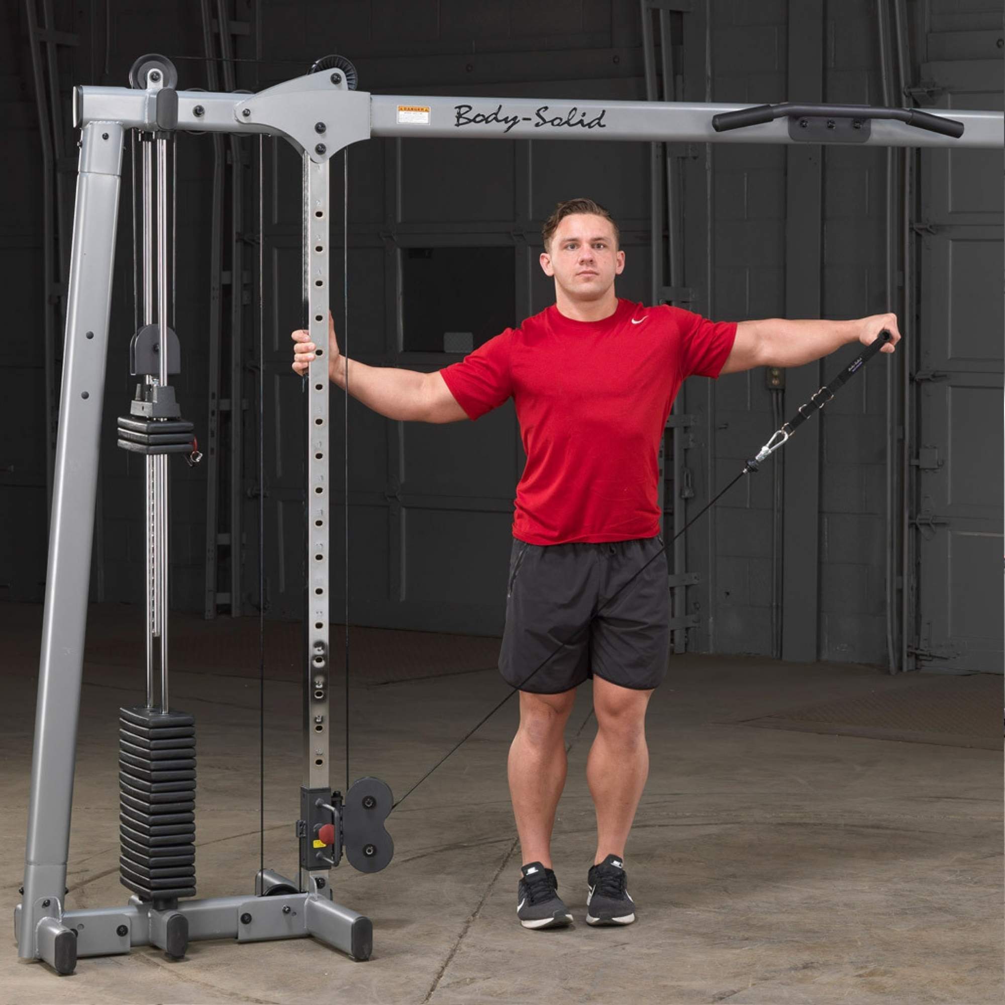 Body-Solid Cable Crossover GDCC250B Man using  cable machine for single-arm lateral raise exercise