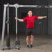 Body-Solid Cable Crossover GDCC250B Man using  cable machine for single-arm lateral raise exercise