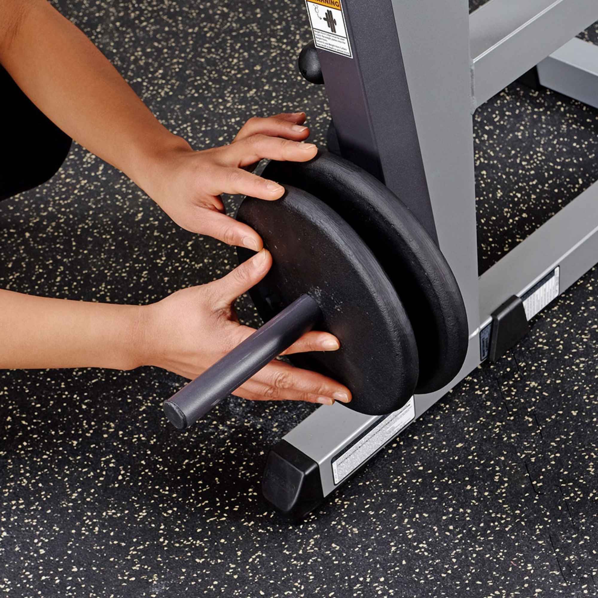 Body-Solid Cam Series Ab & Back Machine GCAB360B Close-up of hands loading weight plates onto the Body-Solid abdominal crunch machine