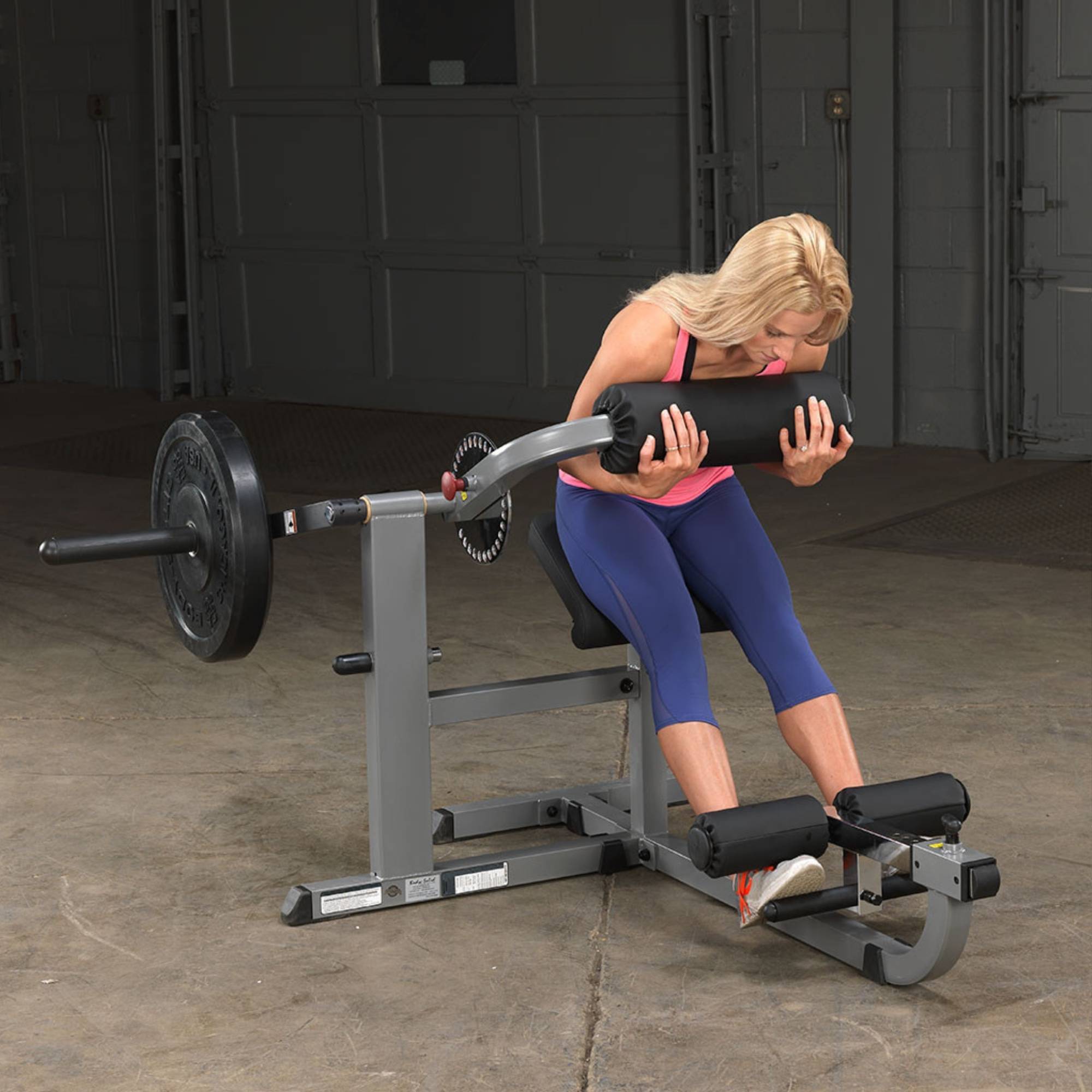 Body-Solid Cam Series Ab & Back Machine GCAB360B Woman executing a forward crunch on the Body-Solid ab machine with a weighted plate