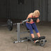 Body-Solid Cam Series Ab & Back Machine GCAB360B Woman executing a forward crunch on the Body-Solid ab machine with a weighted plate