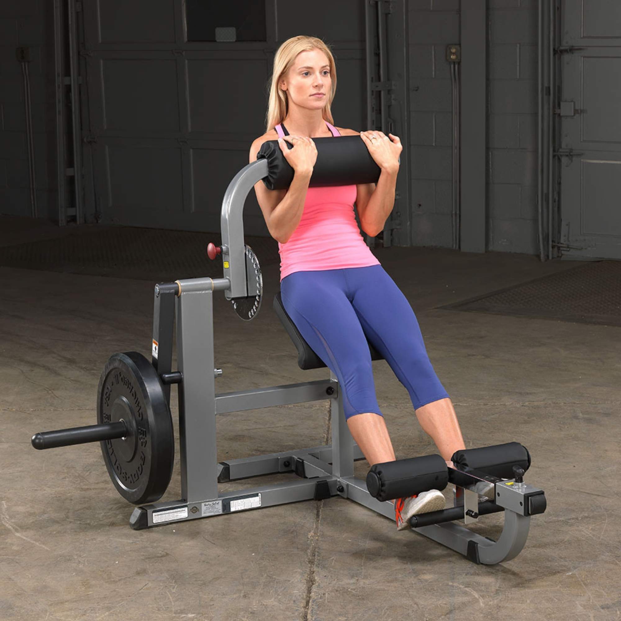 Body-Solid Cam Series Ab & Back Machine GCAB360B Woman performing a seated abdominal crunch on a Body-Solid plate-loaded ab machine with weighted resistance