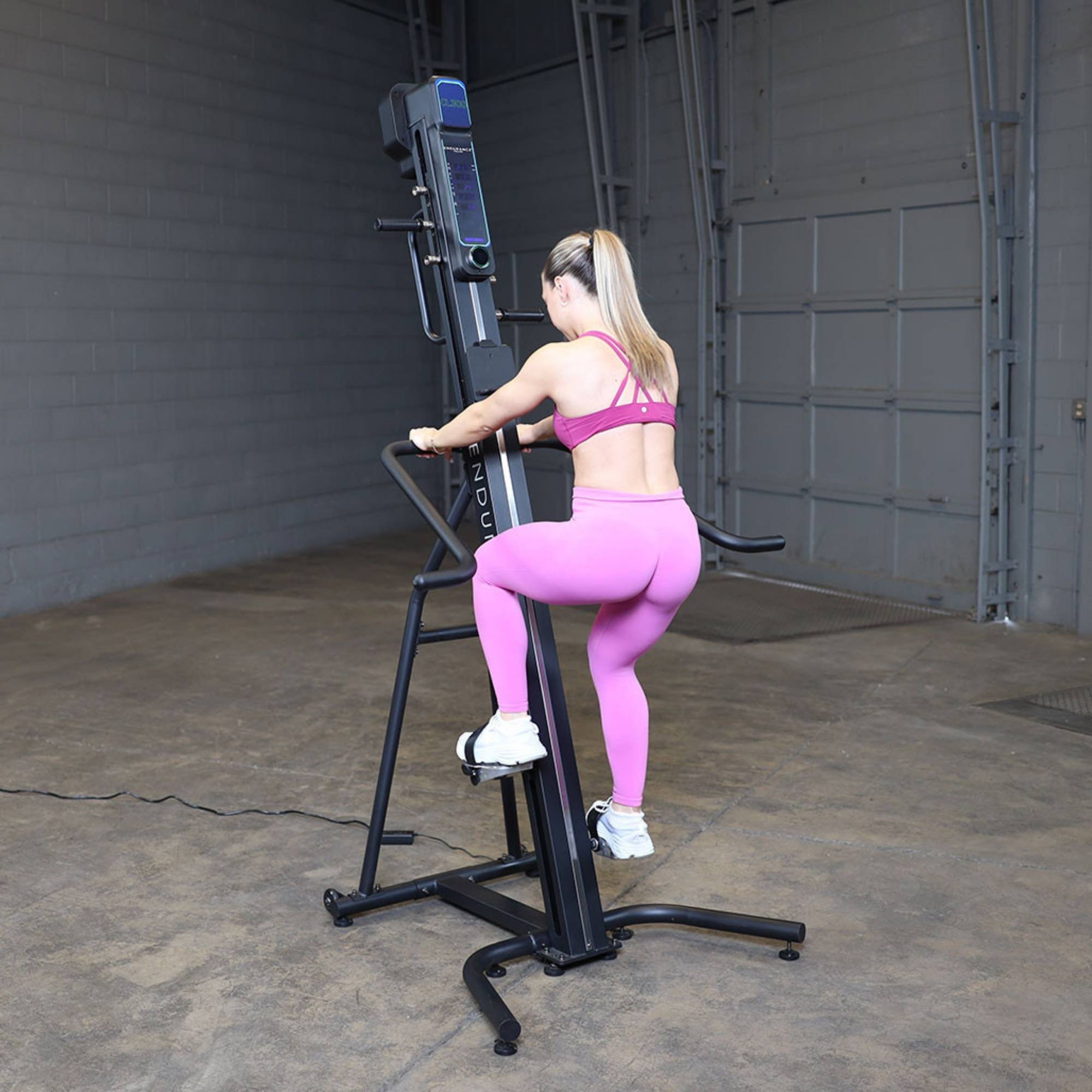 Body-Solid Climber Endurance CL300 Female athlete in pink workout set stepping on Body-Solid Endurance climber for cardio training

