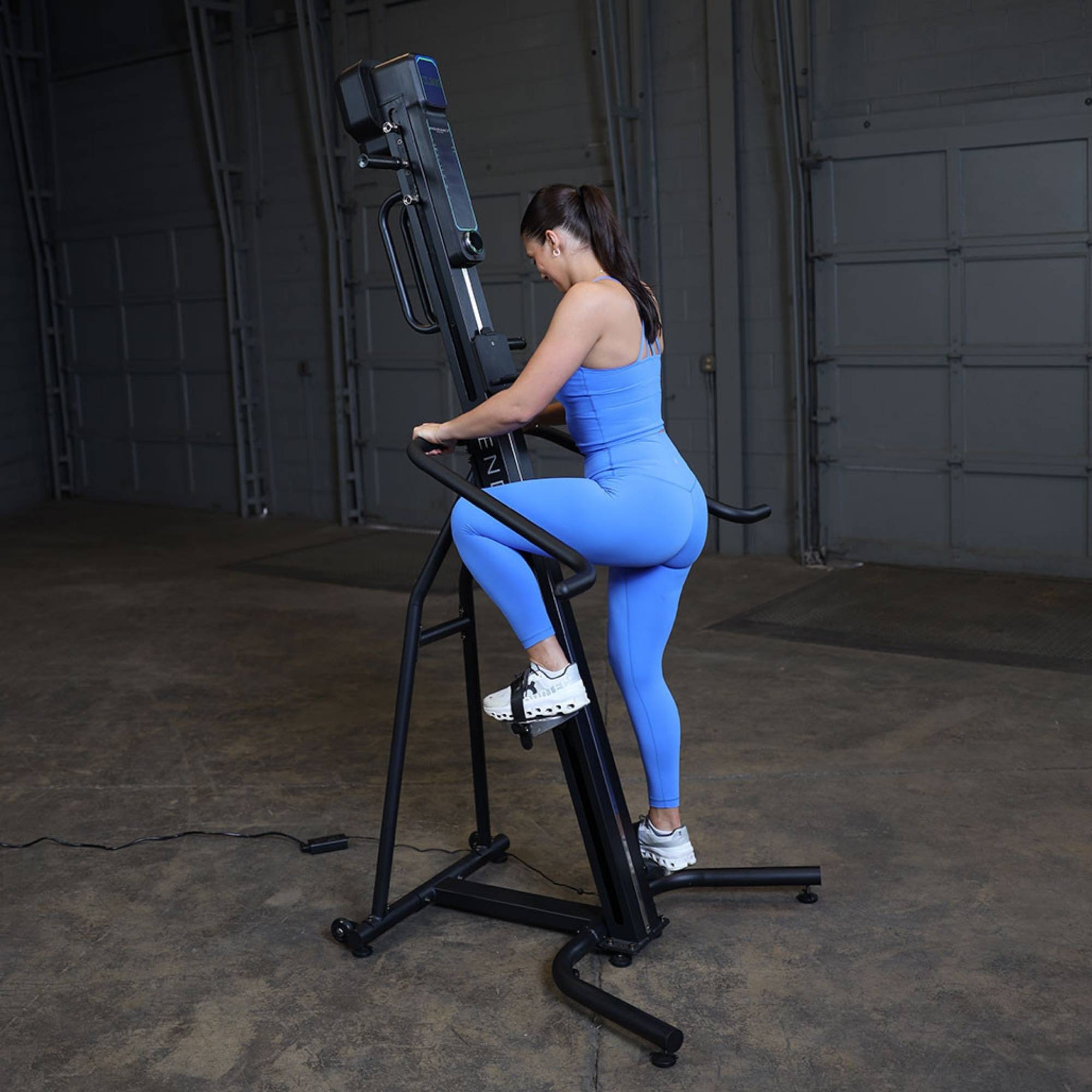 Body-Solid Climber Endurance CL300 Woman using Body-Solid vertical climber in blue activewear inside gym space