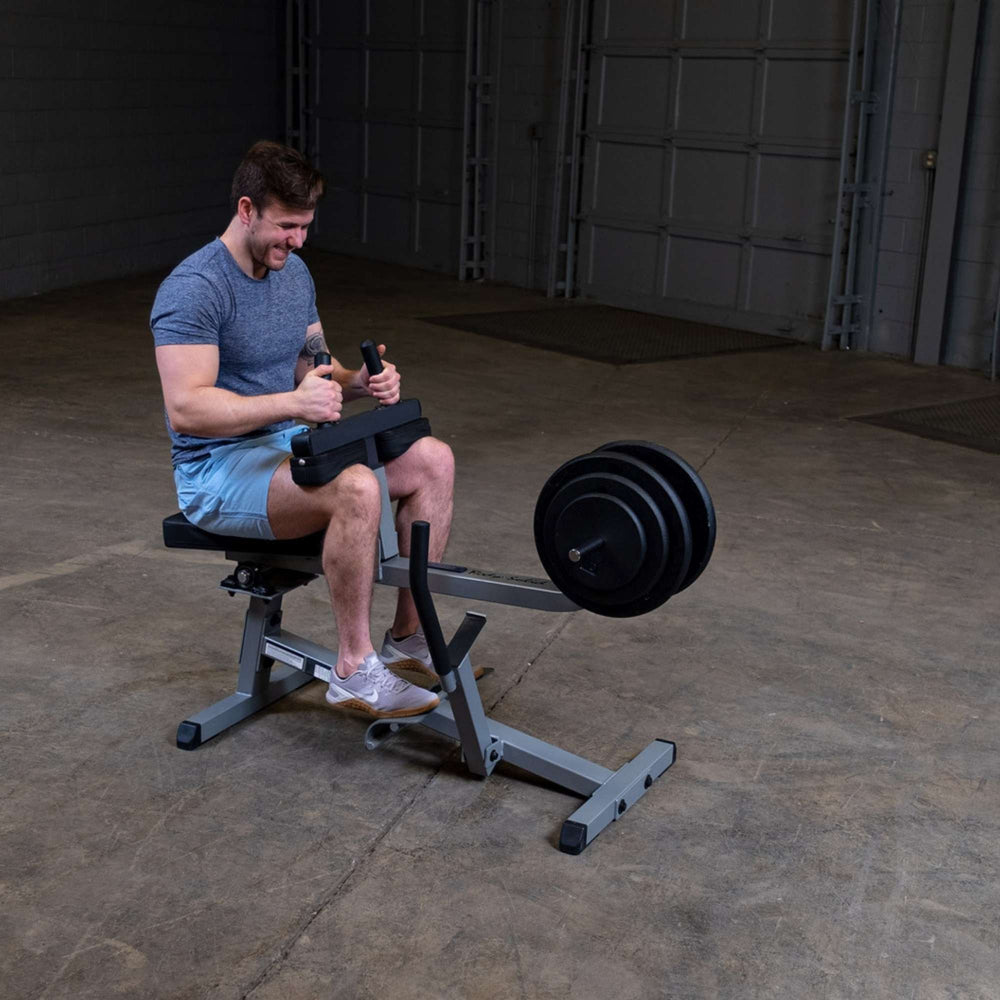 Body-Solid Commercial Seated Calf Raise GSCR349B Man working out on a seated calf raise machine with multiple black weight plates