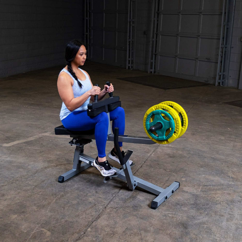Body-Solid Commercial Seated Calf Raise GSCR349B Woman performing calf raises on  seated calf raise machine with colorful Olympic plates