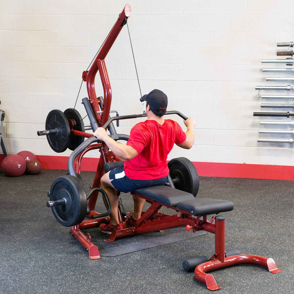 Body-Solid Corner Leverage Gym GLGS100B Back view of a man performing lat pulldown exercise on a red home gym machine with black weights.
