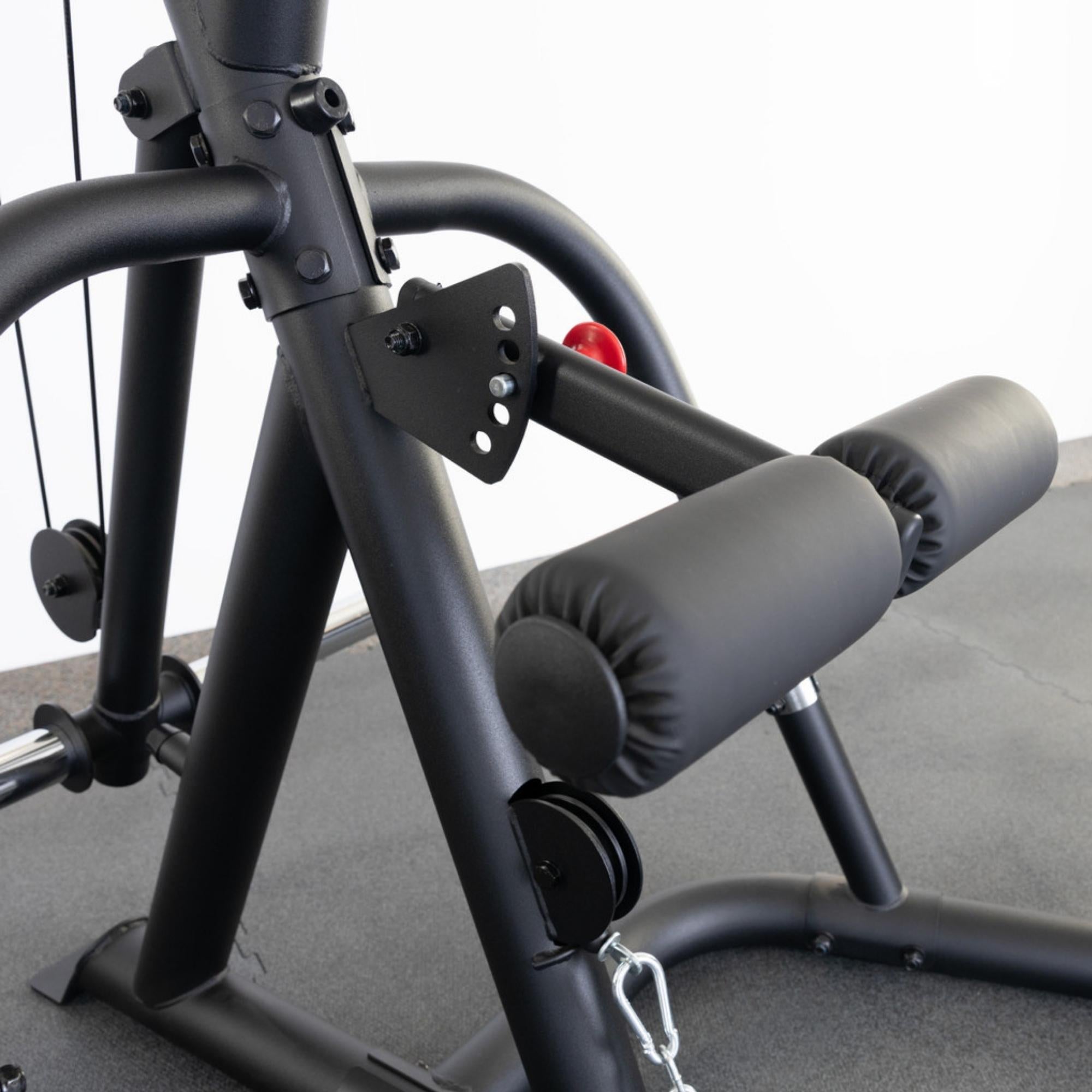 Body-Solid Corner Leverage Gym GLGS100B Close-up angle of leg pad attachment and adjustment plate with black padded rollers and steel chain connection.

