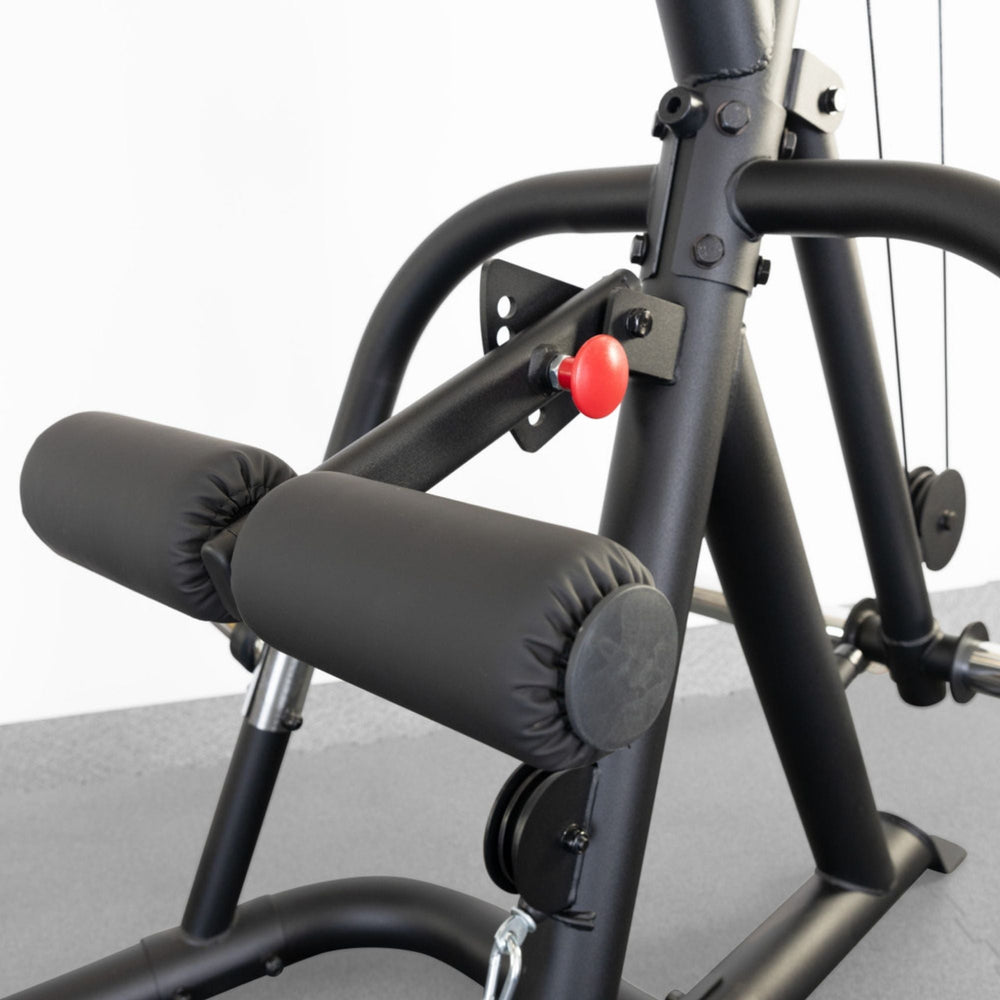 Body-Solid Corner Leverage Gym GLGS100B Close-up of lower frame showing dual padded leg rollers and red adjustment knob on Body-Solid workout machine.
