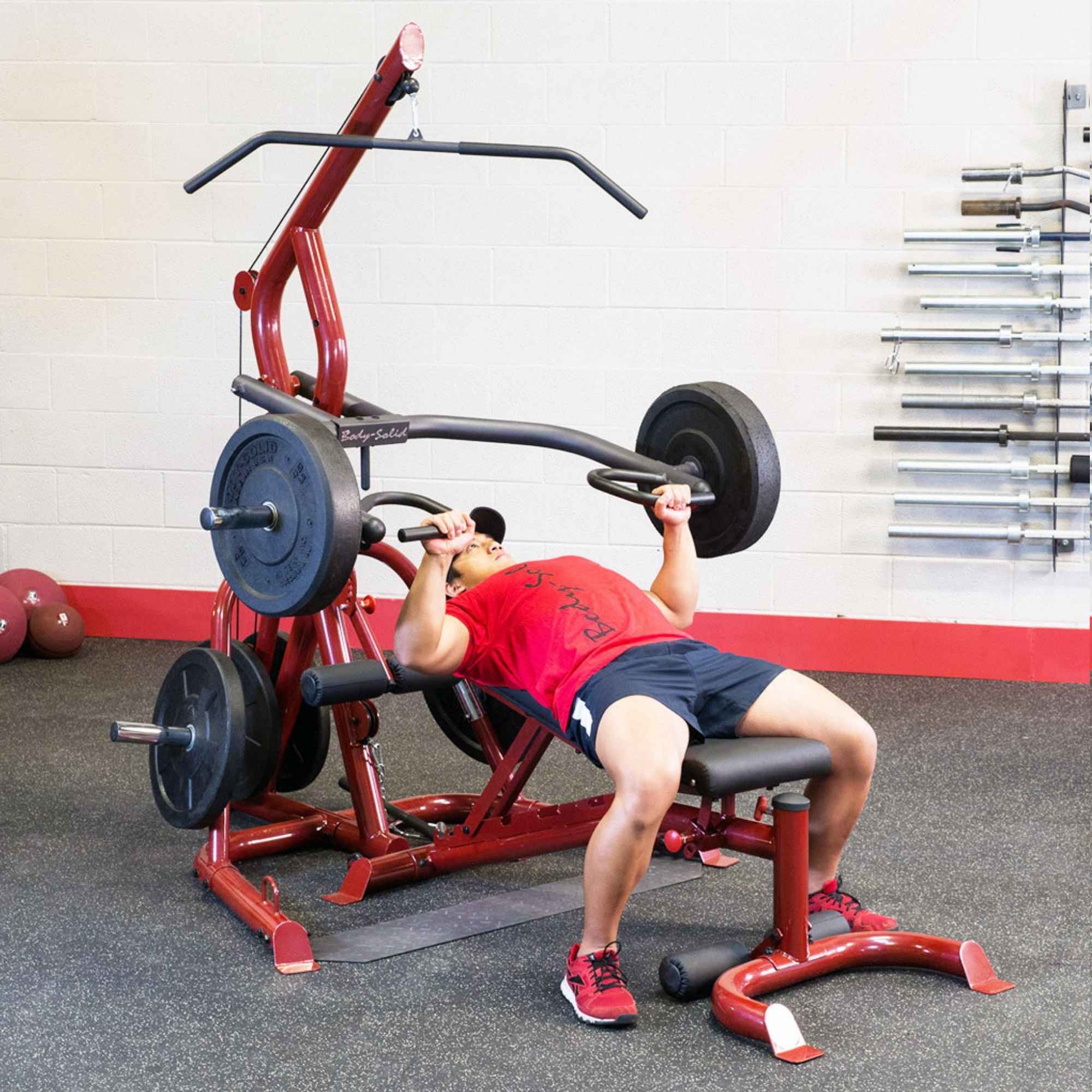 Body-Solid Corner Leverage Gym GLGS100B Man performing incline chest press using a red home gym system with multiple black weight plates.
