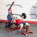 Body-Solid Corner Leverage Gym GLGS100B Man performing incline chest press using a red home gym system with multiple black weight plates.
