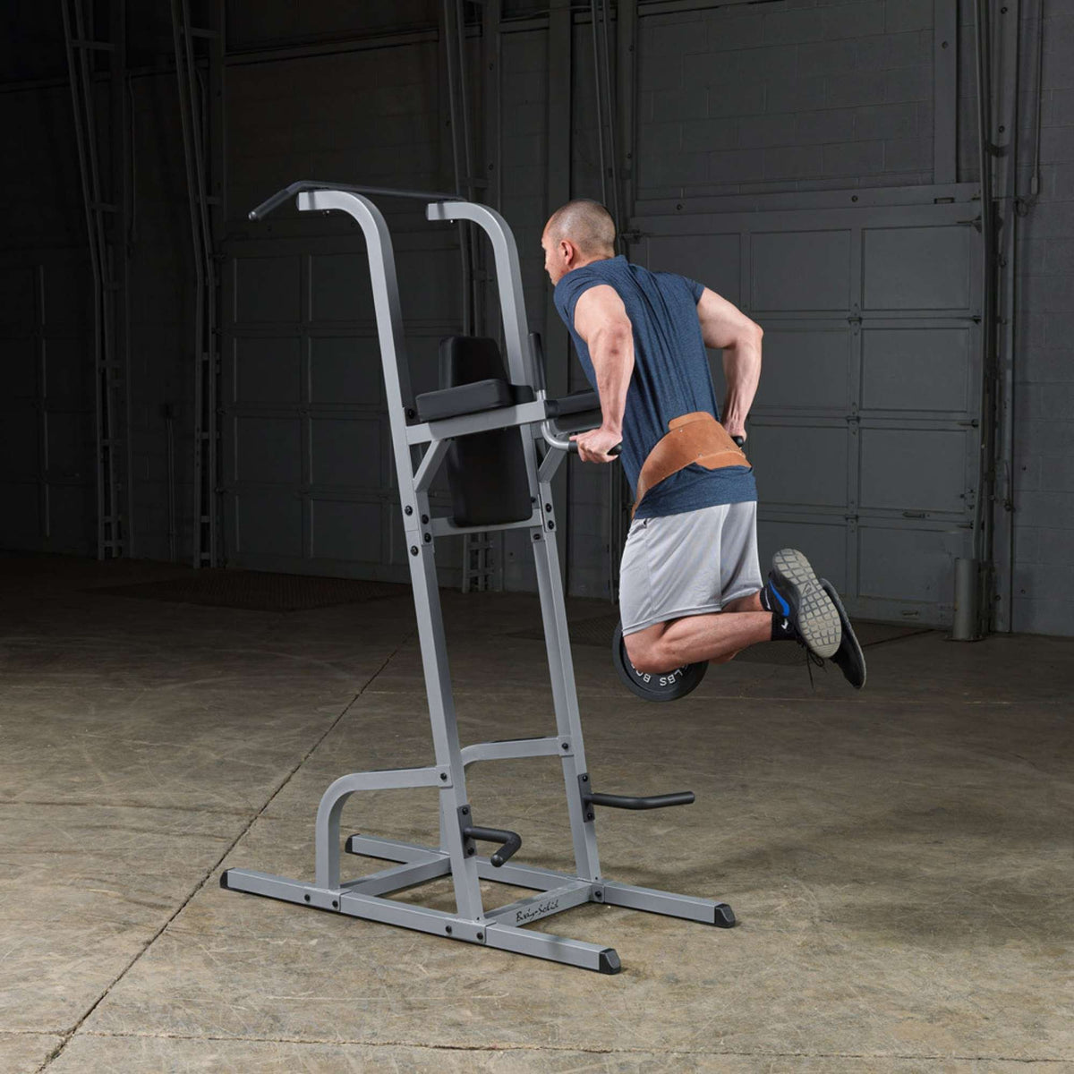 Body-Solid Deluxe Vertical Knee Raise GVKR82B Man performing weighted dips on the Body-Solid Power Tower using a dip belt and plate
