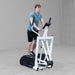 Body-Solid Endurance Center Drive Elliptical E100 Side view of man performing cardio workout on Endurance E100 elliptical machine, showing stride motion and balance.
