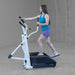 Body-Solid Endurance Center Drive Elliptical E100 Woman performing elliptical training on Endurance E100 machine, demonstrating ergonomic stride and handle use.
