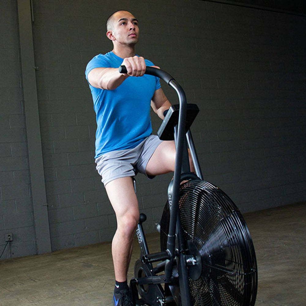 Body-Solid Endurance Dual Action Fan Bike FB300B Man cycling on FB300 air bike for high-intensity interval training