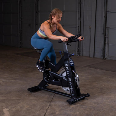 Body-Solid Endurance Indoor Cycle ESB250 Woman riding Body-Solid Endurance ESB250 indoor cycle in gym setting