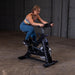 Body-Solid Endurance Indoor Cycle ESB250 Woman riding Body-Solid Endurance ESB250 indoor cycle in gym setting