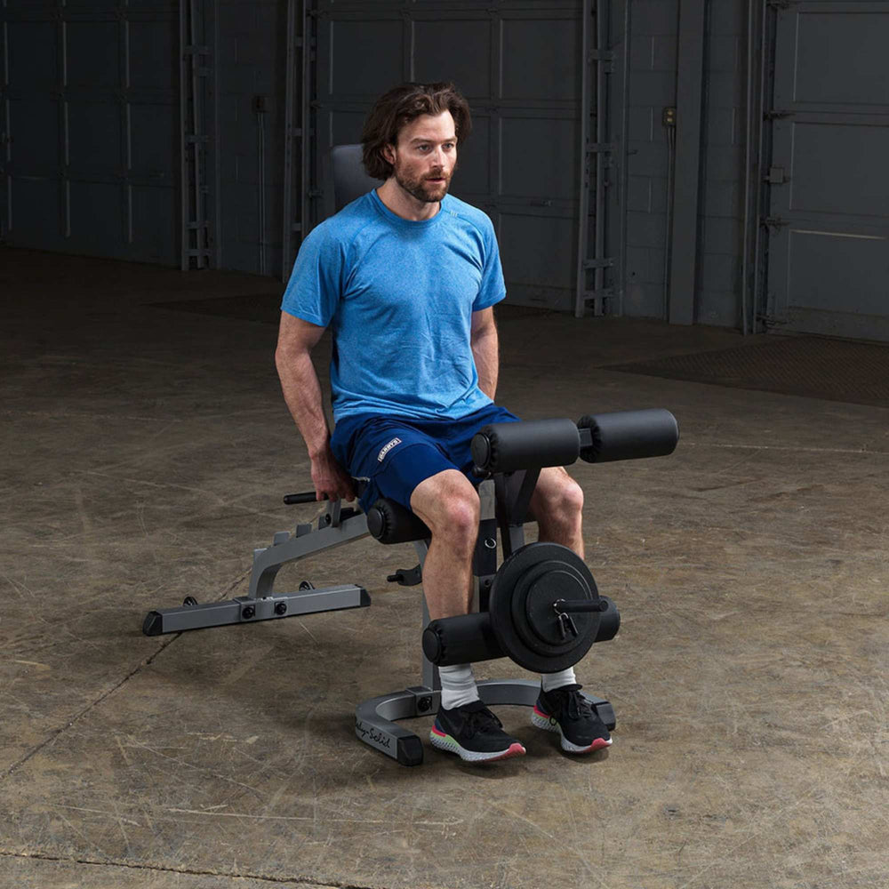 Body-Solid Flat Incline Decline Bench GFID31 Man performing seated leg extension on  adjustable bench with leg developer